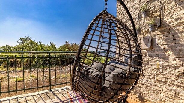 A hanging chair with cushions, a stone wall, and a metal fence. - Holiday Home Ruby, Polje, Croatia (Polje)