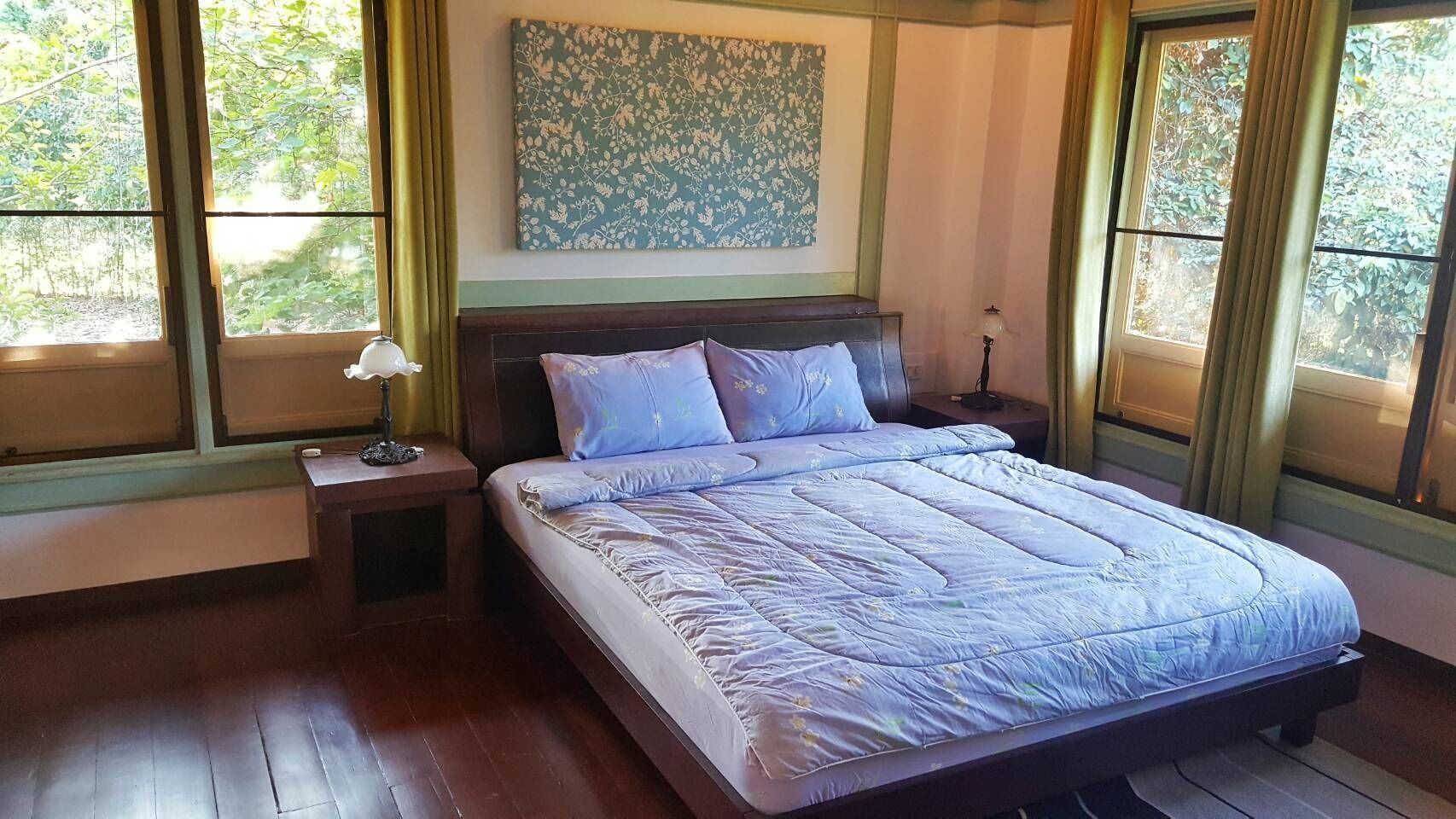 A bedroom with a large bed, a nightstand, a lamp, and a window with curtains.