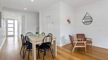 A modern interior with a wooden dining table, black chairs, a brown leather chair, and a wall-mounted mirror.