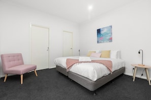Une chambre à coucher avec un lit, une chaise, un tableau et une lampe.
