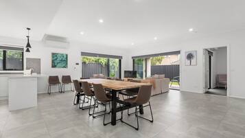 A spacious living area with a dining table and chairs, a kitchen area with a white countertop, and a large window providing a view of the outdoors.