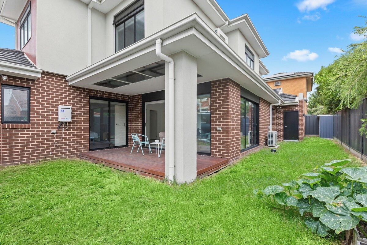A modern house with a covered patio, a brick exterior, and a well-maintained lawn.