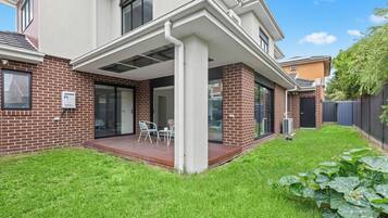 A modern house with a covered patio, a brick exterior, and a well-maintained lawn.