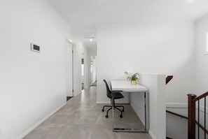 Ein Flur mit weißer Wand, einer Tür und einer Treppe mit Holzgeländer.