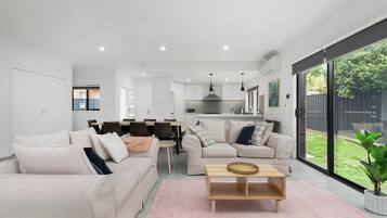 A modern living room with a sofa, coffee table, and dining area.