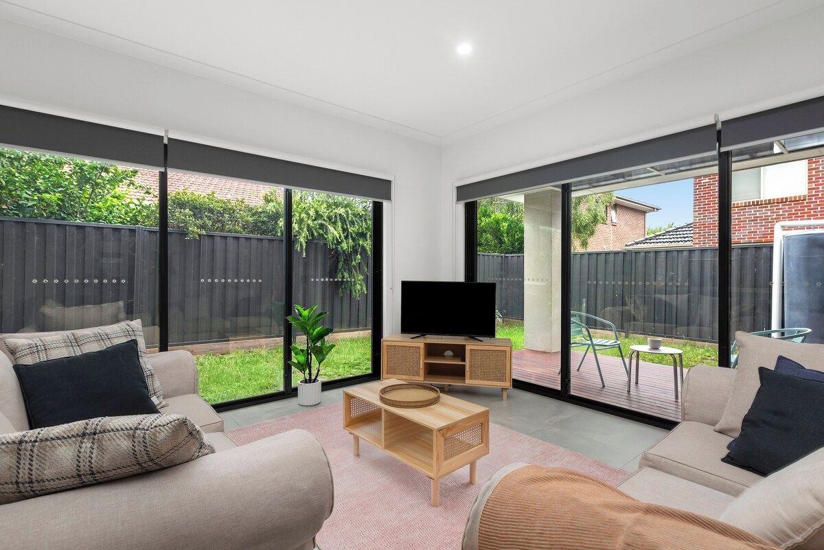 A modern living room with a flat-screen TV, a wooden coffee table, and a sofa.