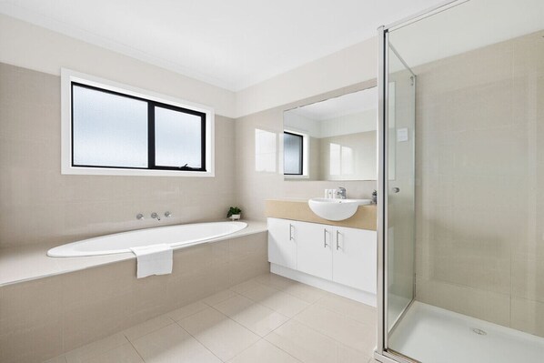 Un bany modern amb banyera, un lavabo i una cabina de dutxa de vidre.