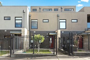 A modern building with a brick facade, multiple windows, and a gated entrance. - Domi Rentals - The Chadstone Homes (Chadstone)