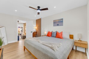A bedroom with a bed, a ceiling fan, a nightstand, a lamp, and a painting on the wall. - Men Only Heated Pool Spa - Kings Cove @Blue Lizard (Oakland Park)