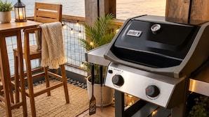 An outdoor patio with a Weber Spirit II grill, wooden chairs, a table, and a view of the water. - Downtown Langley I Beachfront I Whale Watching (Langley)