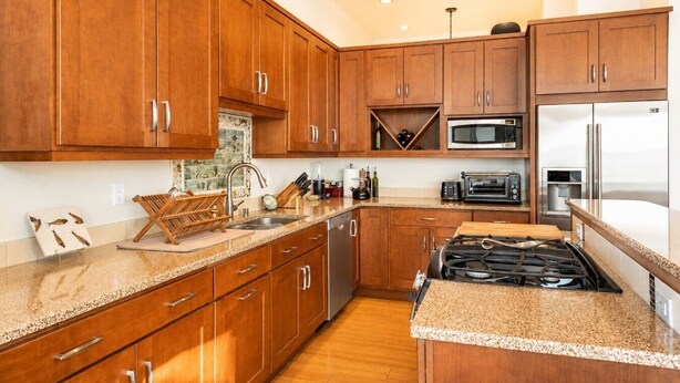 A modern kitchen with wooden cabinets, a gas stove, a microwave, and a refrigerator. - Downtown Langley I Beachfront I Whale Watching (Langley)
