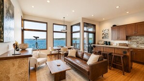 A spacious living area with a large window overlooking the sea, a cozy seating arrangement, and a modern kitchen. - Downtown Langley I Beachfront I Whale Watching (Langley)