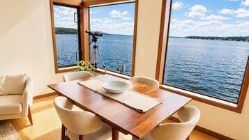 A dining area with a wooden table, four chairs, and a telescope on a tripod.