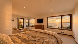 A bedroom with a large bed, a TV, and a view of the water. - Downtown Langley I Beachfront I Whale Watching (Langley)