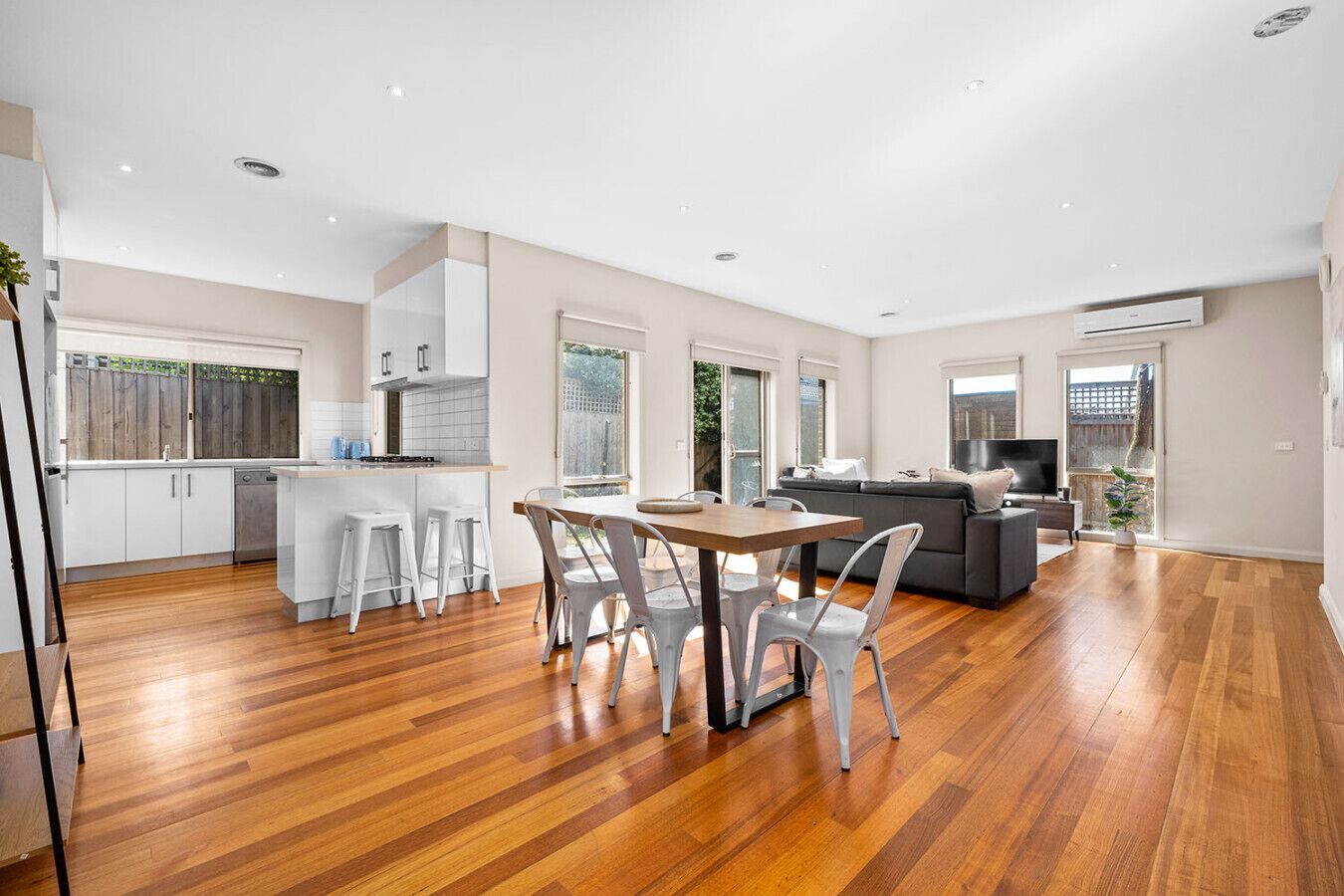 A spacious living area with a dining table, chairs, a sofa, and a TV.