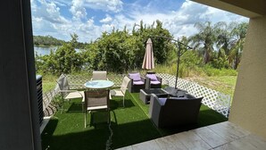 An outdoor patio with a view of a lake, furnished with chairs and a table, surrounded by a white fence. - Condo House 20 min from the Disneyland (Davenport)