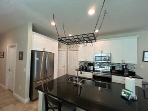 A modern kitchen with stainless steel appliances, a black countertop, and white cabinetry.