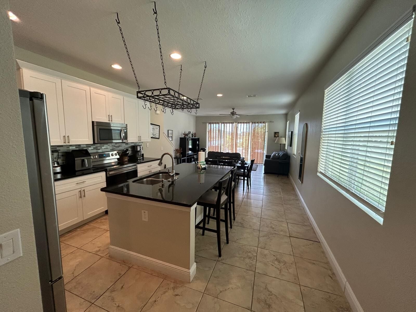 A modern kitchen with a central island, stainless steel appliances, and a dining area with a sofa and chairs.