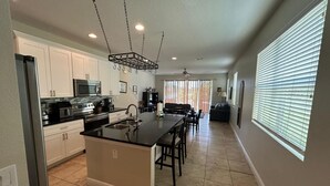 A modern kitchen with a central island, stainless steel appliances, and a dining area with a sofa and chairs. - Condo House 20 min from the Disneyland (Davenport)