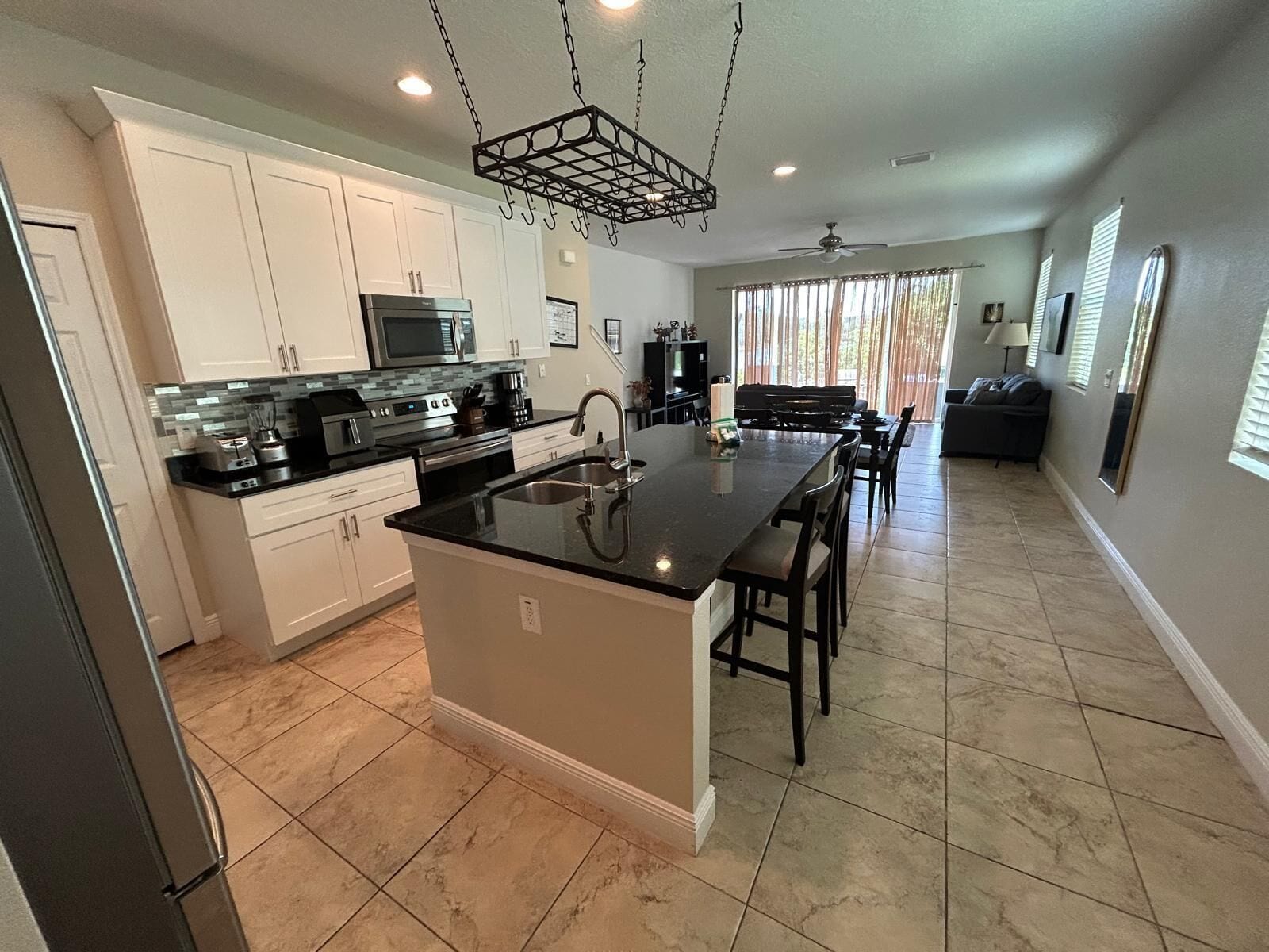 A modern kitchen with white cabinets, a black countertop, and a central island with bar stools.