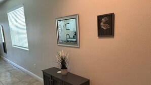 A hallway with a dark-colored console table, a potted plant, and two framed pictures on the wall. - Condo House 20 min from the Disneyland (Davenport)