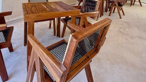 Ein Restaurantinnenraum mit Holztischen, einem reetgedeckten Balken und hängenden Pendelleuchten.