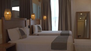 Ein Hotelzimmer mit zwei Betten, einem großen Spiegel und zwei Wandleuchten.