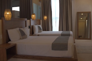 A hotel room with two beds, a large mirror, and two wall-mounted lamps. - Joanza By Ool Hotels (Isla Holbox)