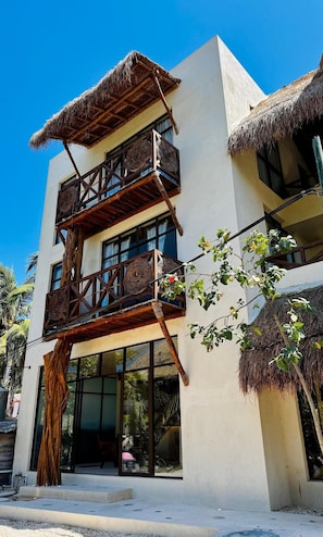 A multi-story building with a balcony, large windows, and a thatched roof. - Joanza By Ool Hotels (Isla Holbox)