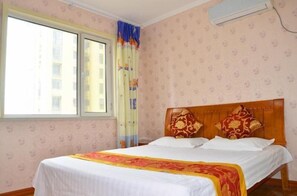Habitació d'hotel amb un llit, una finestra amb cortines i aire condicionat fixat a la paret.