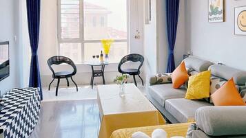 A modern living room with a sofa, a dining table, and a TV.