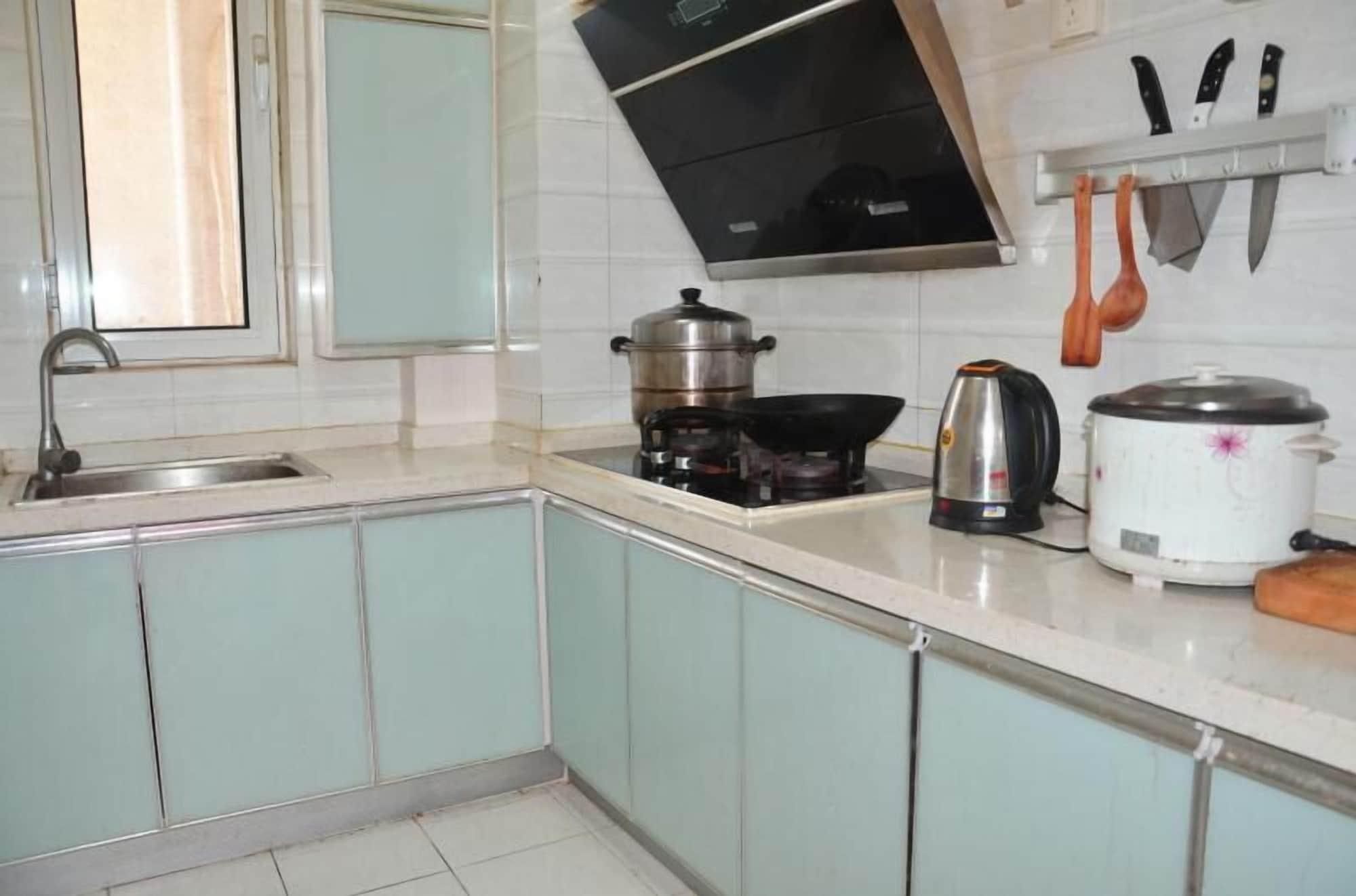 A kitchen with a sink, stove, kettle, and a rice cooker.