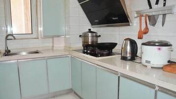 A kitchen with a sink, stove, kettle, and a rice cooker.