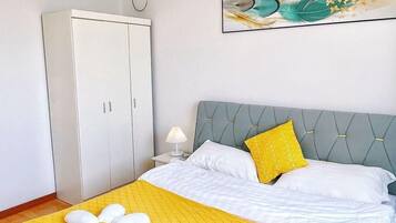A hotel room with a bed, a wardrobe, a painting, and an air conditioning unit.