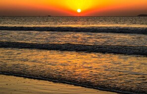 Un capvespre sobre un mar tranquil amb ones que brollen suaument a la riba.