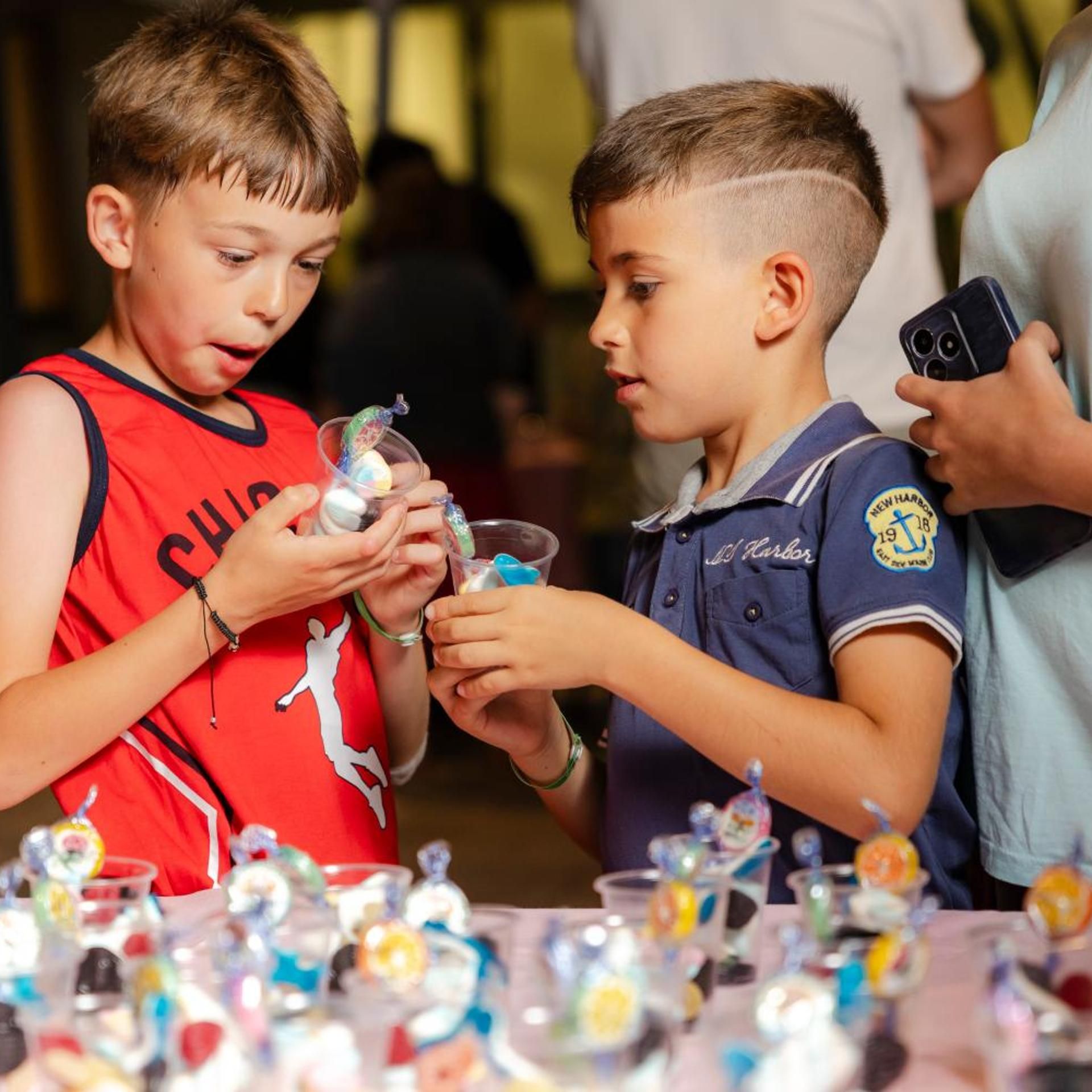 Two children examining items at a table with various objects.