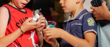 Two children examining items at a table with various objects.