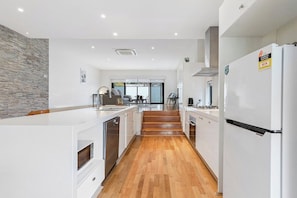 A modern kitchen with white cabinetry, a built-in oven, and a stainless steel refrigerator. - Domi Rentals - The Chadstone Homes (Chadstone)