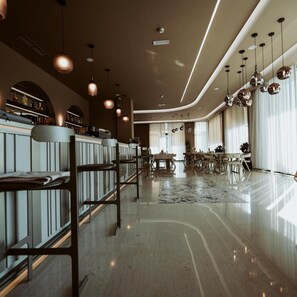A modern hotel lobby with a bar area, seating arrangements, and a large window providing natural light. - Naos Luxury Hotel (Orikum)