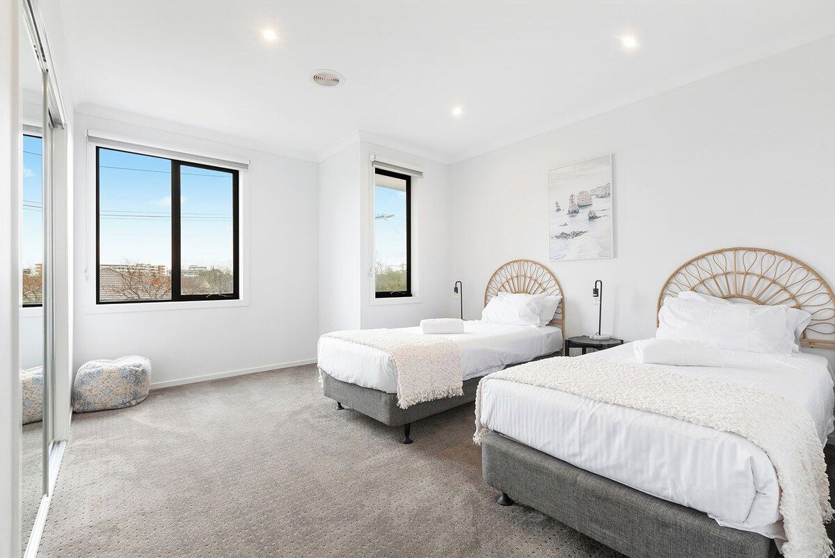 A bedroom with two beds, a large window, and a city view.