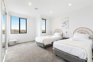 A bedroom with two beds, a large window, and a city view. - Domi Rentals - The Third Residence (Clayton South)