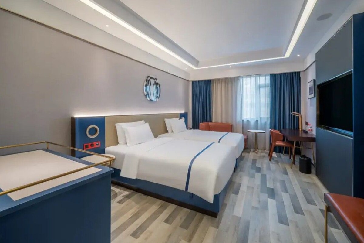 Une chambre d’hôtel avec un grand lit, un bureau, une chaise, une petite table et un téléviseur.