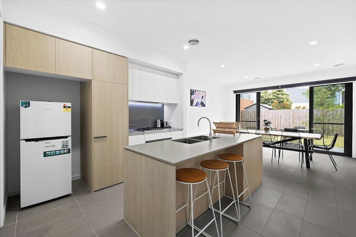 A modern kitchen with a built-in island, bar stools, and a dining area with a view.