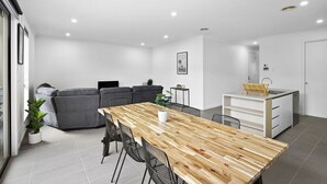 Une cuisine moderne avec une table en bois, un canapé gris et un petit îlot central doté d’un évier.