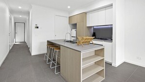 Une cuisine moderne dotée d’un îlot central, de tabourets de bar et d’une cuisinière intégrée.