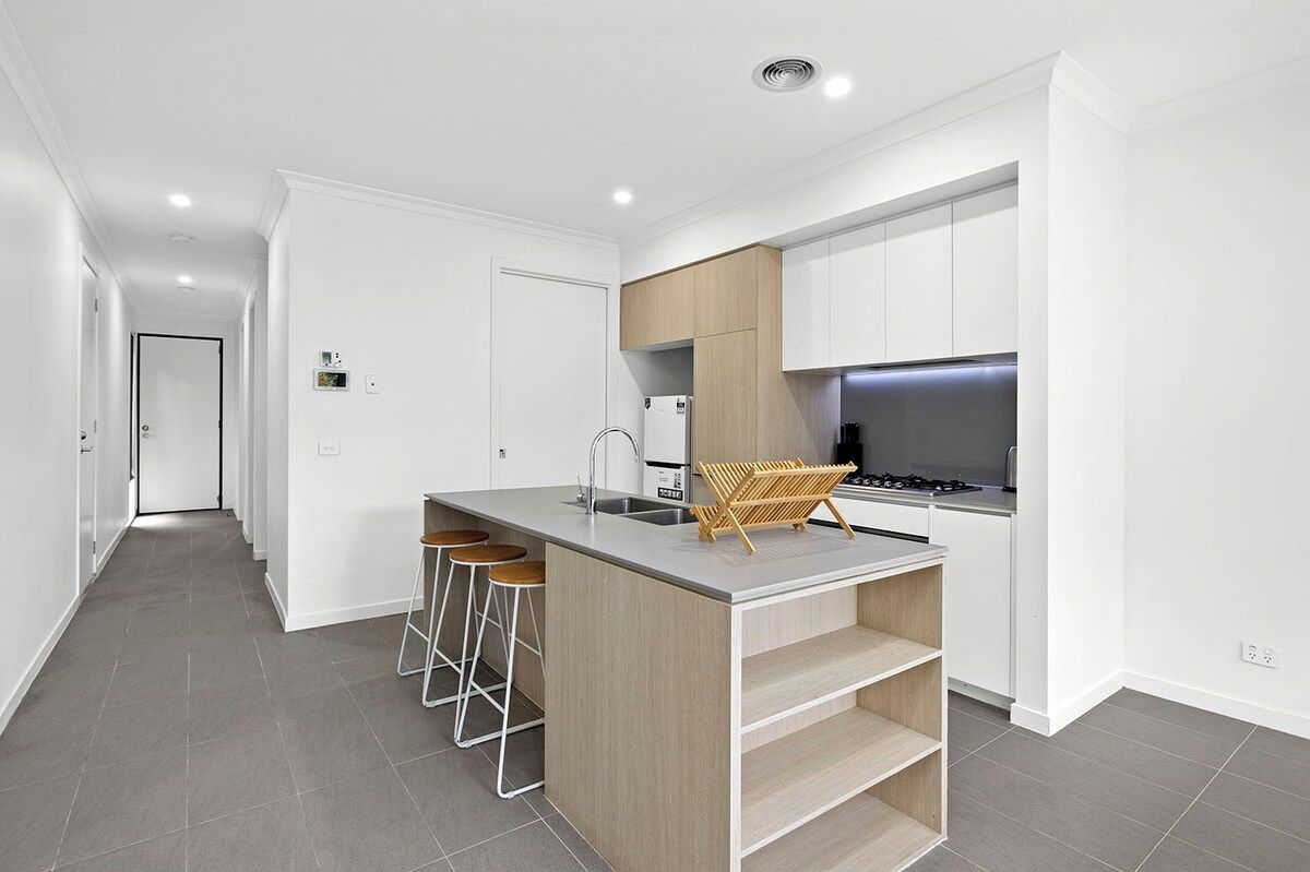 A modern kitchen with a central island, bar stools, and a built-in stove.