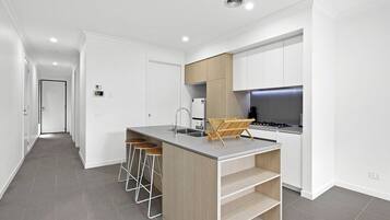 A modern kitchen with a central island, bar stools, and a built-in stove.