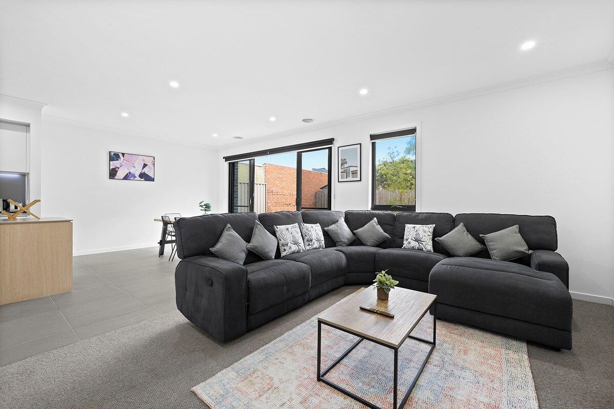 A modern living room with a sectional sofa, a coffee table, and a rug.