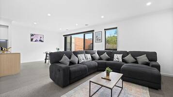 A modern living room with a sectional sofa, a coffee table, and a rug.