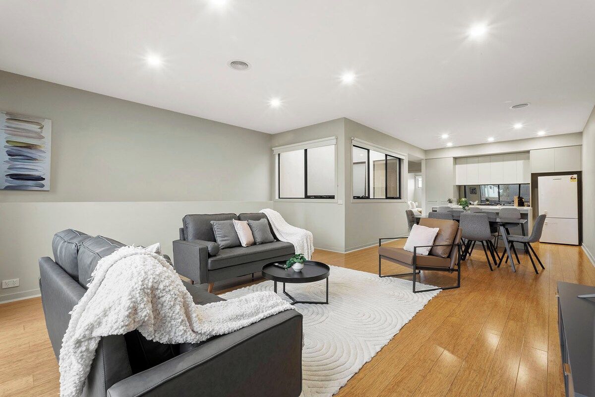 A modern living room with a grey sofa set, a coffee table, and a dining area with a table and chairs.